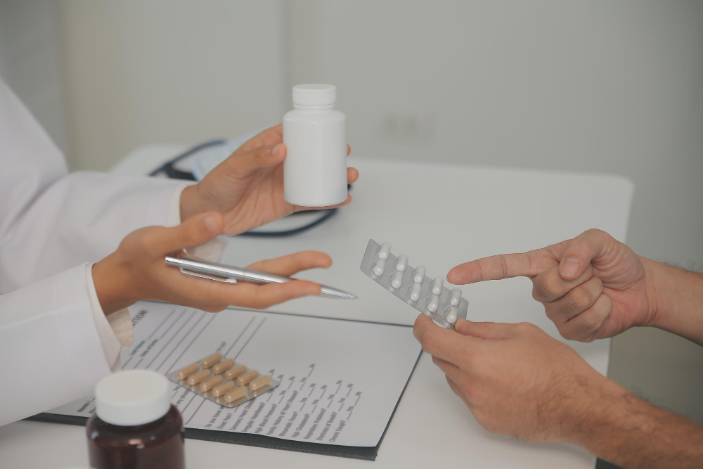 Doctor and patient discussing medication, with pill blister pack and prescription bottle on a table