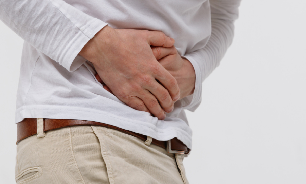Person holding their stomach, indicating abdominal pain or discomfort."